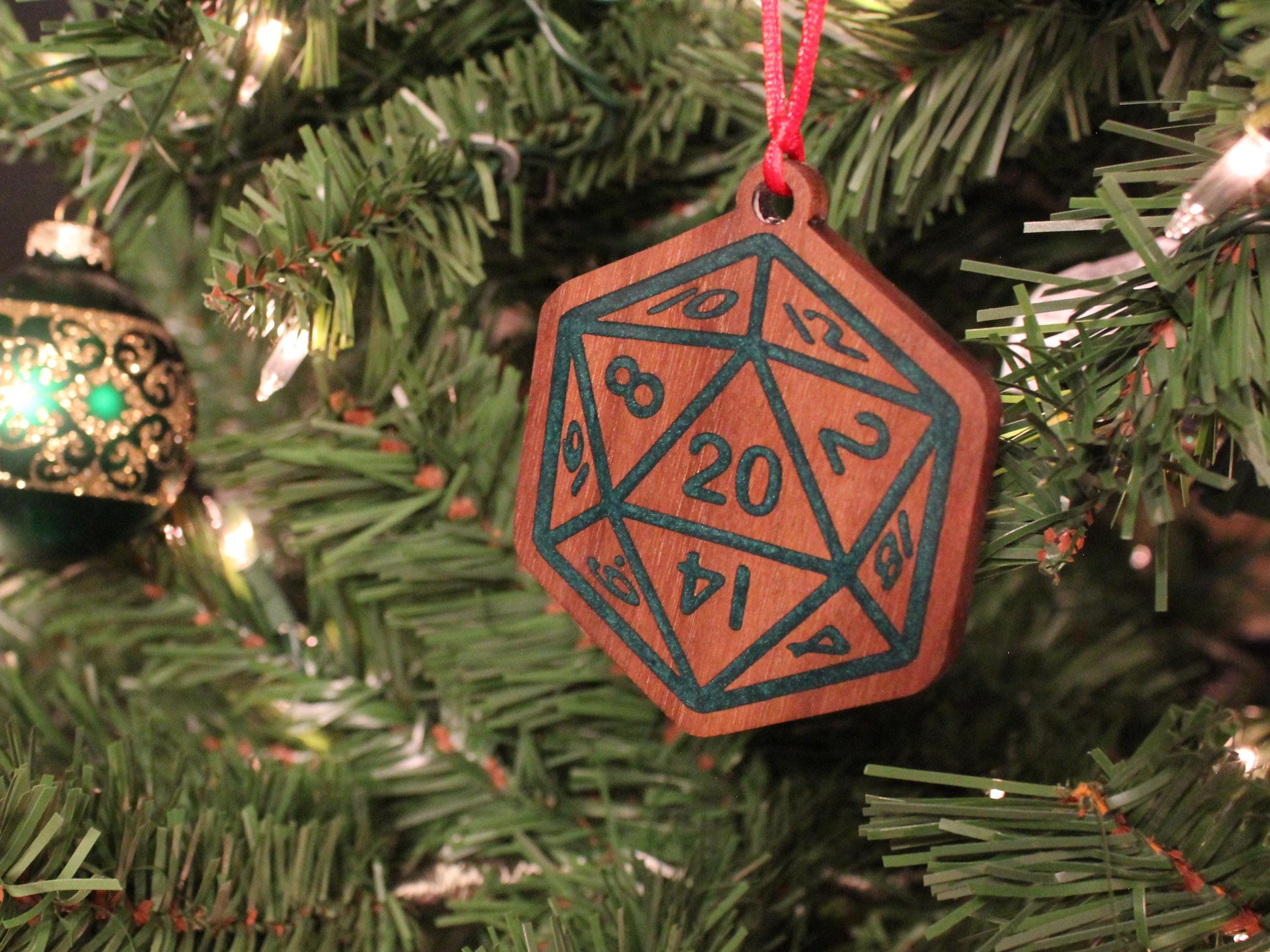 Black Walnut Christmas ornament in the style of a D20 dice, with a green resin infilled engraving.